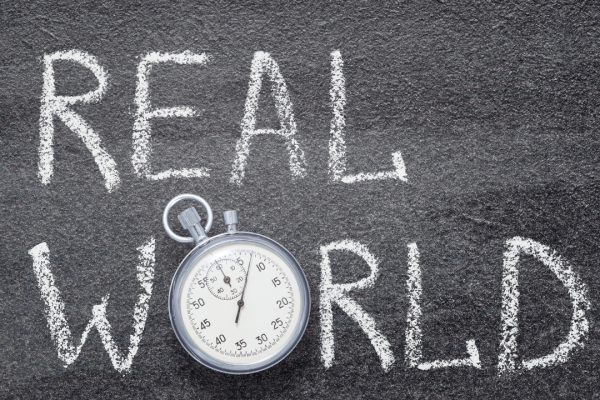 Graphis of words Real World written in chalk with a stopwatch on top of the letter O