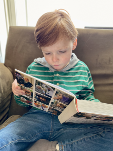 A young boy with Lennox-Gastaut syndrome caused by a variation on the CACNA1C gene is engrossed in a book full of faces.